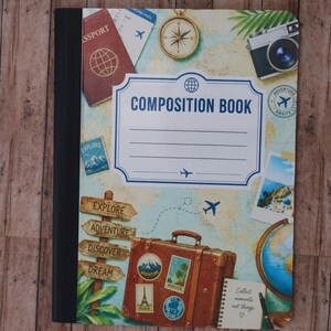 May include: A composition book with a travel-themed cover featuring a map background, a brown suitcase with stickers, a camera, a compass, a passport, and a signpost. The center label reads COMPOSITION BOOK with lines for writing.