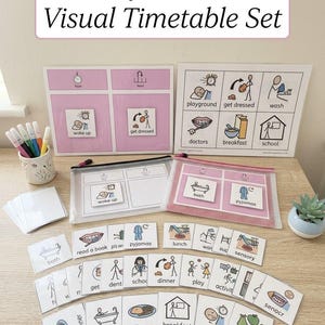 May include: A daily routine visual timetable set featuring two large laminated boards with pink and white sections, two clear zippered pouches, and numerous small square cards with black line drawings and text labels for activities like wake up, bath, and school.