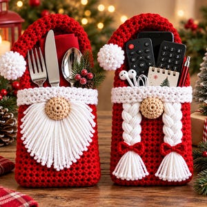 Könnte beinhalten: Zwei rote Häkeltaschen in Form von Weihnachtswichteln. Die linke Tasche enthält eine silberne Gabel, ein Messer und einen Löffel mit einer roten Serviette. Die rechte Tasche enthält zwei schwarze Fernbedienungen, ein Notizbuch und weiße Ohrhörer.