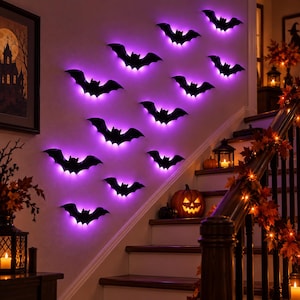 May include: A collection of black bat-shaped wall decorations arranged in a diagonal pattern on a wall. Each bat is backlit with a vibrant purple glow, creating a silhouette effect against the wall surface. The bats vary in size and wing position.
