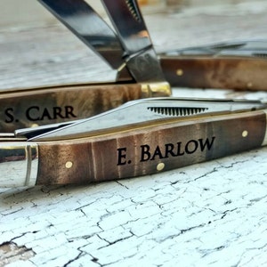May include: Two pocket knives with wooden handles. The top knife has the name "S. CARR" engraved on the handle. The bottom knife has the name "E. BARLOW" engraved on the handle.