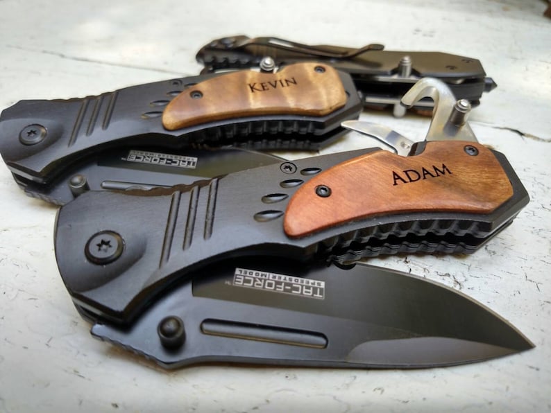 May include: Two black pocket knives with wooden handles. The handles are engraved with the names "Kevin" and "Adam".