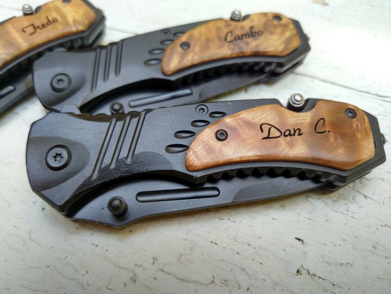 May include: Three personalized pocket knives with wood handles. The handles are engraved with the names "Fredo", "Cambo", and "Dan C."