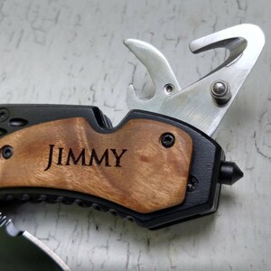 May include: A black multi-tool with a wood handle. The handle is engraved with the name "JIMMY".