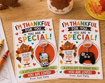 Könnte beinhalten: Zwei rechteckige Karten mit dem Text I'M THANKFUL FOR YOU... YOU ARE SPECIAL! A LITTLE GIFT TO REMIND YOU... YOU ARE LOVED! From: Aunt Patty. Eine Karte zeigt einen Boba-Tee-Schlüsselanhänger, die andere einen schwarzen Gamecontroller-Schlüsselanhänger.