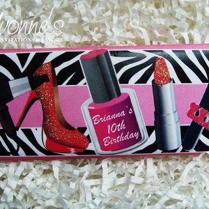 May include: A pink and black zebra print chocolate bar wrapper with a pink stripe across the middle. The wrapper features images of a red high heel shoe, a red nail polish bottle, a red lipstick, and a nail file. The text "Brianna's 10th Birthday" is printed on the wrapper.
