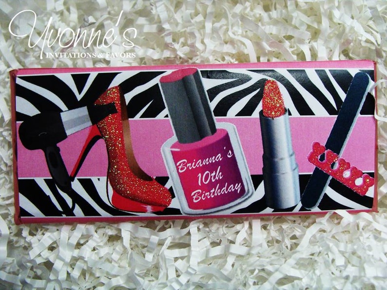 May include: A pink and black zebra print chocolate bar wrapper with a pink stripe across the middle. The wrapper features images of a red high heel shoe, a red nail polish bottle, a red lipstick, and a nail file. The text "Brianna's 10th Birthday" is printed on the wrapper.