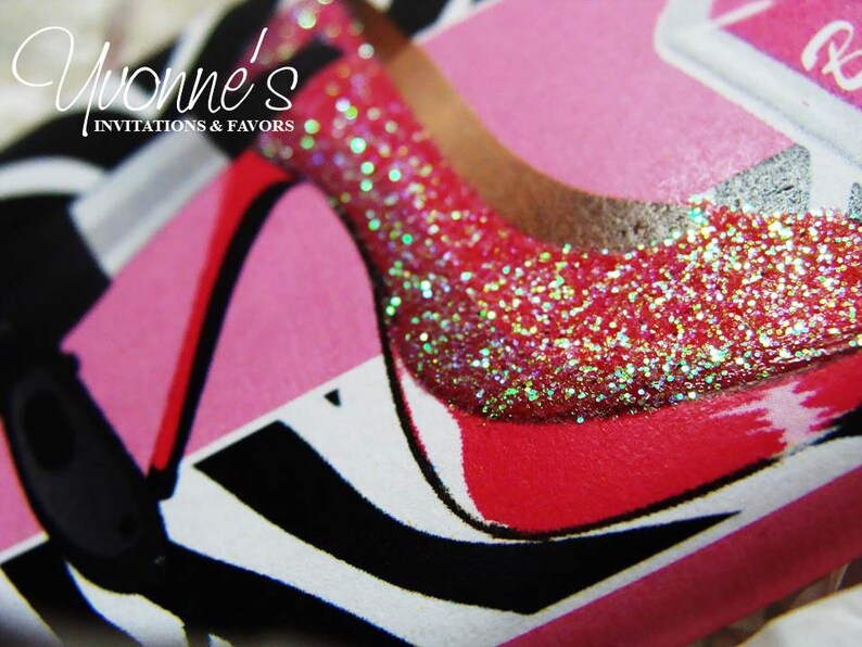 May include: Close-up of a pink and red high heel shoe with glitter on the toe. The shoe is on a white background with black and white stripes.