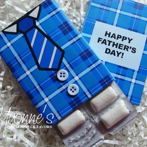 May include: A blue and white plaid gift box with a tie and buttons on the front. The box is open to reveal a pack of chewing gum. The box has a card on top that says "Happy Father's Day!"