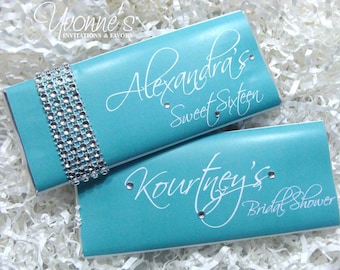 May include: Two turquoise blue chocolate bar wrappers with white text. The top wrapper says "Alexandra's Sweet Sixteen" and the bottom wrapper says "Kourtney's Bridal Shower".