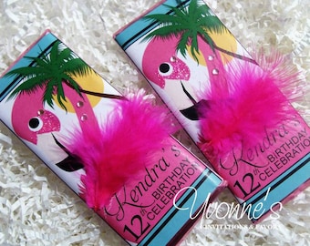 May include: Two pink flamingo chocolate bar wrappers with pink feathers. The wrappers have a blue and white background with palm trees and the text "Kendra's 12th Birthday Celebration".