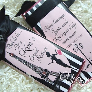 May include: Pink and black chocolate bar wrapper with a black ribbon bow. The wrapper features a silhouette of the Eiffel Tower, a woman in a dress, and the text "Ooh la la... It's Kim's Sweet Sixteen". The back of the wrapper has the text "Merci beaucoup... You've made Kim's special day extra sweet! September 15, 2019".