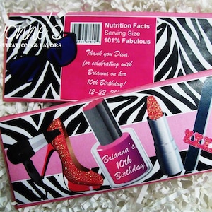May include: Pink and black zebra print favor boxes with a pink background. The boxes feature images of makeup items, including lipstick, nail polish, and a nail file. The text on the boxes reads "Brianna's 10th Birthday!" and "Nutrition Facts Serving Size 101% Fabulous".