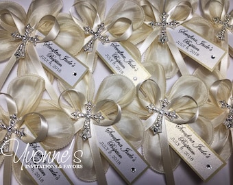 May include: Ivory satin and tulle bows with a rhinestone cross charm and a personalized tag that reads "Serafina Jude's Baptism July 8, 2018".