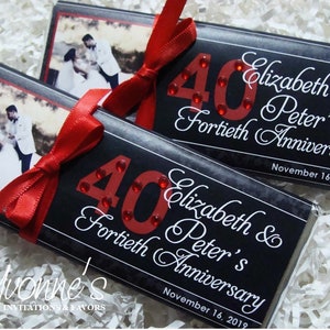May include: Two black chocolate bar wrappers with a red ribbon and a red number 40 with rhinestones. The wrappers have a photo of a couple and the text "Elizabeth & Peter's Fortieth Anniversary November 16, 2019".