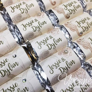 May include: A collection of white and silver favor boxes with a seahorse and seashell design. The boxes are decorated with the names "Jessie & Dylan" in green lettering.