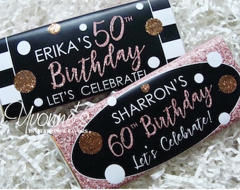May include: Two black and white chocolate bar wrappers with pink glitter. The top wrapper says "ERIKA'S 50th Birthday Let's Celebrate!" The bottom wrapper says "SHARRON'S 60th Birthday Let's Celebrate!"