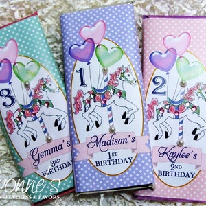 May include: Three personalized chocolate bar wrappers with a carousel horse, balloons, and polka dots. The wrappers are in pink, purple, and green. The text on the wrappers reads "Gemma's 3rd Birthday", "Madison's 1st Birthday", and "Kaylee's 2nd Birthday".