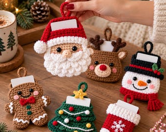 Puede incluir: Un conjunto de seis adornos navideños de ganchillo que representan a Santa Claus, un reno, un muñeco de nieve, un hombre de jengibre, un árbol de Navidad y un calcetín, cada uno con una ranura rectangular blanca para tarjetas de regalo.