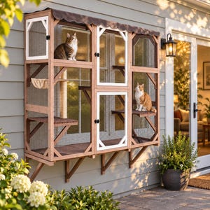 May include: A wooden outdoor cat enclosure mounted to a wall, featuring multiple levels, wire mesh panels, white-framed doors, and a dark scalloped roof. Two cats are positioned inside the structure on different wooden platforms.
