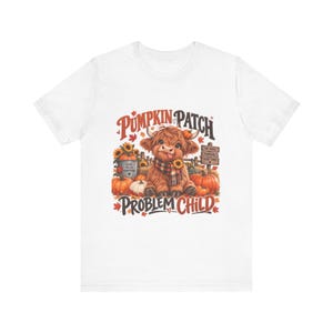 Peut inclure: Un t-shirt blanc avec une illustration d'une vache highland brune et poilue tirant la langue, entourée de citrouilles orange, de tournesols et d'un panneau en bois indiquant Hay Rides, Pumpkins, Good Times. Le texte PUMPKIN PATCH PROBLEM CHILD est imprimé.