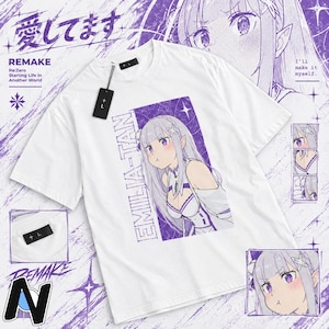 May include: A white short-sleeve t-shirt featuring a purple graphic print of the anime character Emilia from Re:Zero. The design includes the text EMILIA-TAN, Japanese characters, and a black brand tag attached to the collar with a string.