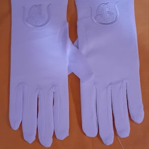 May include: A pair of white gloves with an embroidered design on the back of each hand. The design features a stylized head with a crown and a crescent moon.