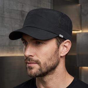 May include: A solid black military-style cap featuring a structured crown, a curved brim, and breathable mesh side panels. The cap includes a small, rectangular grey reflective tab detail on the side near the lower edge of the crown.