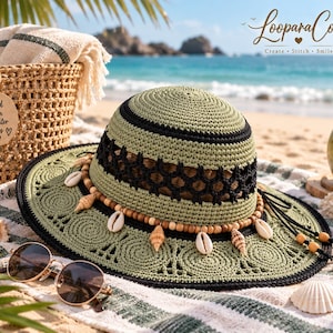 Puede incluir: Un sombrero de ganchillo verde salvia con una banda de celosía negra, una hilera de cuentas de madera y conchas colgantes. El sombrero tiene un ala ancha con patrones circulares y un borde negro, junto a unas gafas de sol.