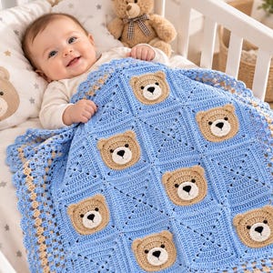 May include: A handmade crochet baby blanket featuring a repeating pattern of light blue squares and tan teddy bear faces with black embroidered noses and eyes. The blanket has a decorative scalloped border in light blue and tan yarn.