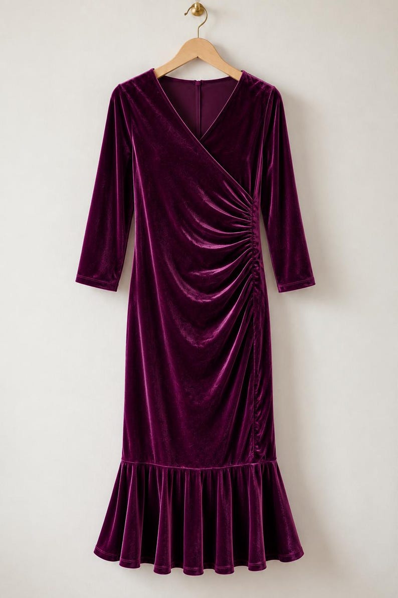 May include: A deep purple velvet dress featuring a V-neckline, three-quarter length sleeves, and a side-ruched waist detail. The garment has a fitted bodice that transitions into a flared, ruffled hemline, hanging from a wooden hanger.