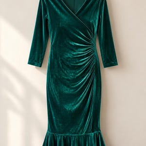 May include: A dark emerald green velvet dress featuring a V-neckline, three-quarter length sleeves, and a fitted bodice with side ruching. The skirt has a flared, ruffled hemline that falls below the knee, creating a distinct silhouette.