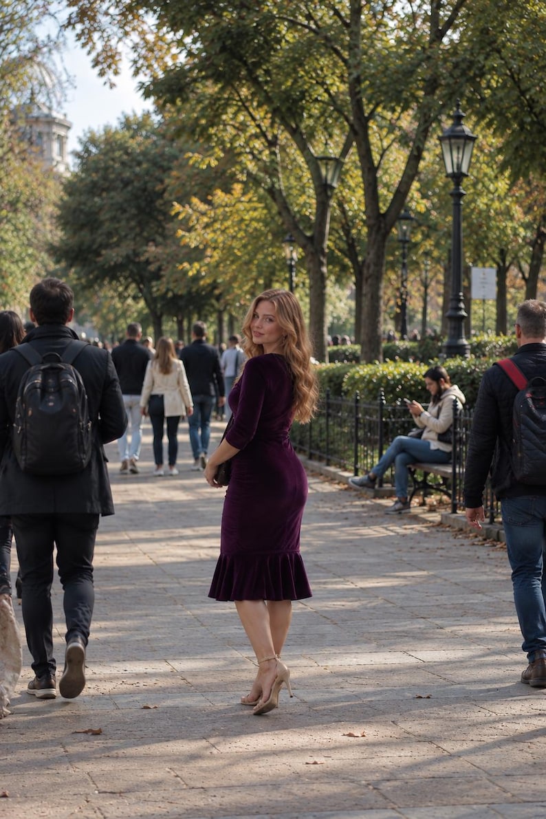 May include: A deep purple velvet dress featuring three-quarter length sleeves, a form-fitting bodice, and a ruffled hemline that falls below the knee, paired with light-colored high-heeled sandals worn in an outdoor park setting.