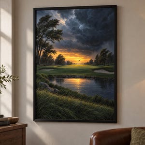 May include: A framed wall art print depicting a golf course landscape at sunset. The scene features a green fairway, sand bunkers, and a pond in the foreground, with dark, dramatic storm clouds overhead and a bright orange glow on the horizon.