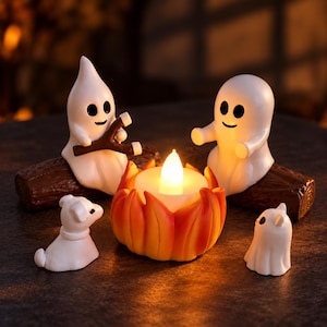 May include: Two white ghost figurines sit on brown logs, one holding a brown slingshot. A central orange and yellow flame-shaped light glows brightly. Two smaller white ghost figures sit on the ground near the illuminated campfire centrepiece.