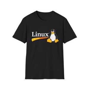 Op de afbeelding: Een zwart t-shirt met korte mouwen voorzien van de witte tekst Linux en een afbeelding van de Tux-pinguïnmascotte met een witte buik, zwart lichaam en oranje voeten en snavel, geplaatst boven een horizontale oranje swoosh-afbeelding.