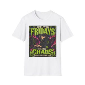 Puede incluir: Una camiseta blanca de manga corta con un estampado gráfico de un personaje estilo anime frente a un ordenador. El texto dice I DEPLOY ON FRIDAYS BECAUSE CHAOS BUILDS CHARACTER en letras verde lima y blancas sobre un fondo oscuro con llamas.