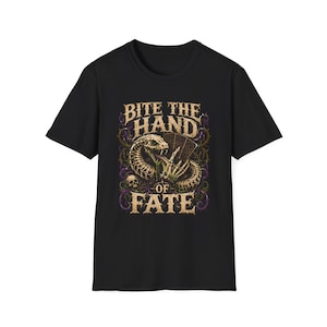 以下が含まれることがあります： 黒の半袖Tシャツ。トランプを持つ骸骨の手と、その周りに巻き付く蛇のグラフィックがプリントされている。中央のイラストの上下には、かすれたフォントで「BITE THE HAND OF FATE」という文字がデザインされている。
