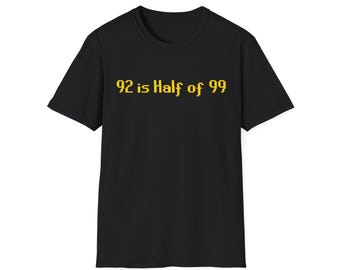 Könnte beinhalten: Ein schwarzes Kurzarm-T-Shirt mit dem gelben, verpixelten Text 92 is Half of 99, der mittig auf der Brust platziert ist. Das Kleidungsstück hat einen Rundhalsausschnitt und eine Standardpassform mit kontrastreicher Typografie auf dunklem Stoff.