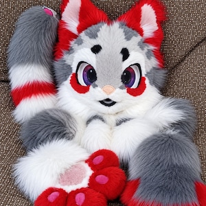 May include: A plush animal costume head and paws set featuring long faux fur in shades of grey, white, and vibrant red. The head has large purple eyes, pointed ears with red tips, and a white muzzle. The paws are red with pink paw pads.