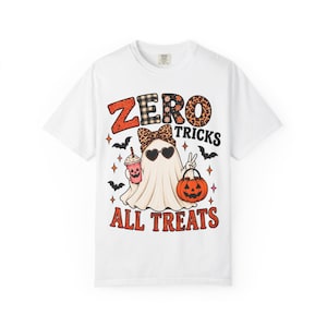Puede incluir: Una camiseta blanca de manga corta con el gráfico de un fantasma con un lazo de leopardo y gafas de sol en forma de corazón. El fantasma sostiene un cubo de calabaza y una bebida. El texto dice ZERO TRICKS ALL TREATS con murciélagos y estrellas.
