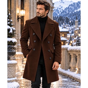 May include: A brown double-breasted wool-blend overcoat featuring wide lapels, six dark buttons arranged in two vertical rows, and two side flap pockets. The coat is worn over a black turtleneck sweater and black trousers, creating a layered look.