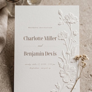 Puede incluir: Una tarjeta de invitación de boda blanca con detalles florales en relieve en el lado derecho. El texto dice: Wedding Invitation, Charlotte Miller and Benjamin Devis, saturday, october 17, 2026, 5:00 pm, the glasshouse, new york, ny.