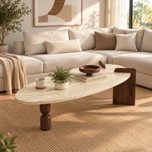 Puede incluir: Una mesa de centro ovalada con un tablero de piedra travertino beige con vetas naturales, sostenida por dos patas de madera marrón oscuro. Una pata tiene forma cilíndrica apilada, mientras que la otra es un panel rectangular plano y vertical.