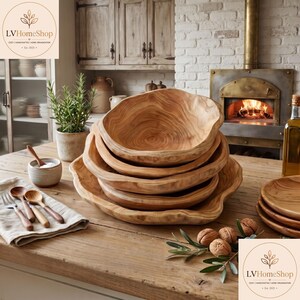 K&ouml;nnte beinhalten: Ein Stapel aus vier Schalen aus Naturholz mit unregelm&auml;&szlig;igen, organischen R&auml;ndern und sichtbarer Maserung. Die Schalen sind auf einer Holzoberfl&auml;che neben einer kleinen Keramikschale mit Holzl&ouml;ffel, einer Leinen-Serviette und Waln&uuml;ssen platziert.
