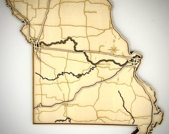 Peut inclure: Une carte en bois découpée au laser de l'État du Missouri présentant des noms de villes gravés tels que Kirksville, St. Joseph, Jefferson City, Springfield et Poplar Bluff, ainsi que des réseaux routiers, des rivières et une rose des vents.