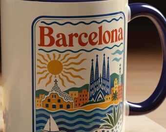 May include: A cream-colored ceramic mug with a dark blue interior and handle. The front features a colorful graphic illustration of the Barcelona cityscape, including the Sagrada Familia, a sun, a sailboat, and the text Barcelona in red.