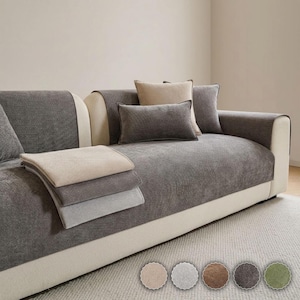 May include: A sofa covered in dark gray textured fabric covers, featuring a beige square pillow and a dark gray rectangular pillow. A stack of folded beige and gray fabric covers rests on the seat. Five circular color swatches are displayed below.