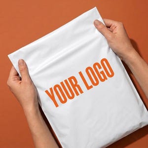May include: A white rectangular poly mailer shipping bag featuring the text YOUR LOGO printed in bold orange capital letters across the center. The bag is constructed from a smooth, opaque plastic material with a sealed top edge and side seams.