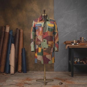 Könnte beinhalten: Eine langärmelige Jacke aus einem Patchwork aus mehrfarbigen Lederbahnen in den Farben Rot, Gelb, Grün, Blau und Braun. Die Jacke verfügt über einen Kragen, eine Knopfleiste auf der Vorderseite und vier rechteckige Taschen mit Klappen.